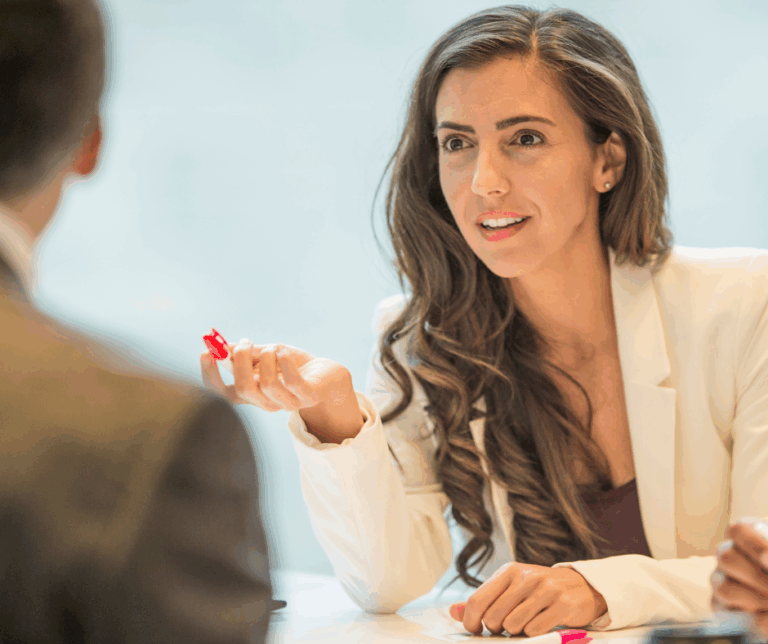 Femme souriante en discussion avec un homme, stylo à la main, illustrant une négociation salariale