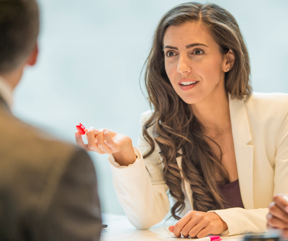 Femme souriante en discussion avec un homme, stylo à la main, illustrant une négociation salariale